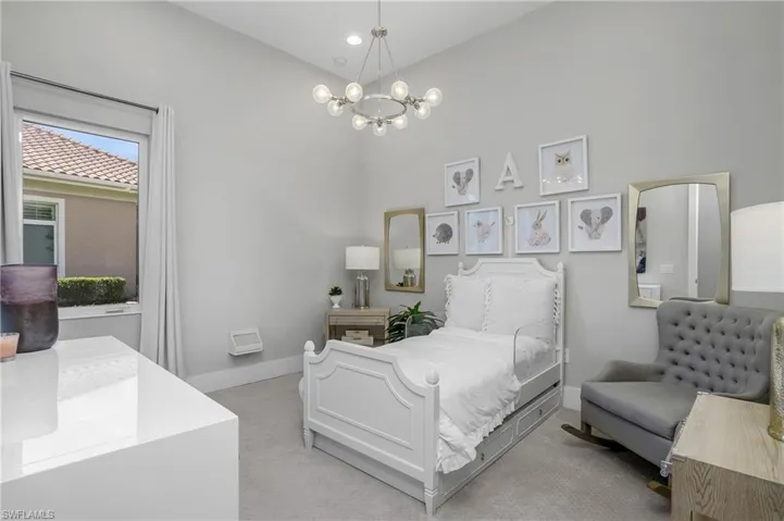 Bedroom with a high ceiling, light carpet, and an inviting chandelier