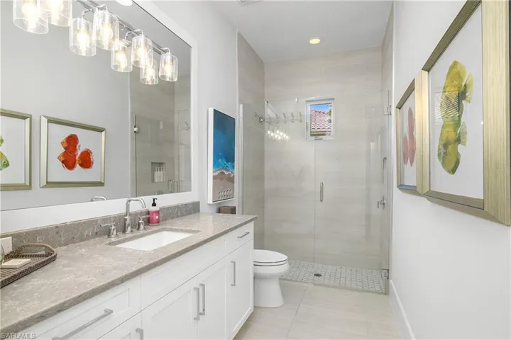 Spacious guest bath also serves as pool bath and includes large vanity and frameless walk-in shower.
