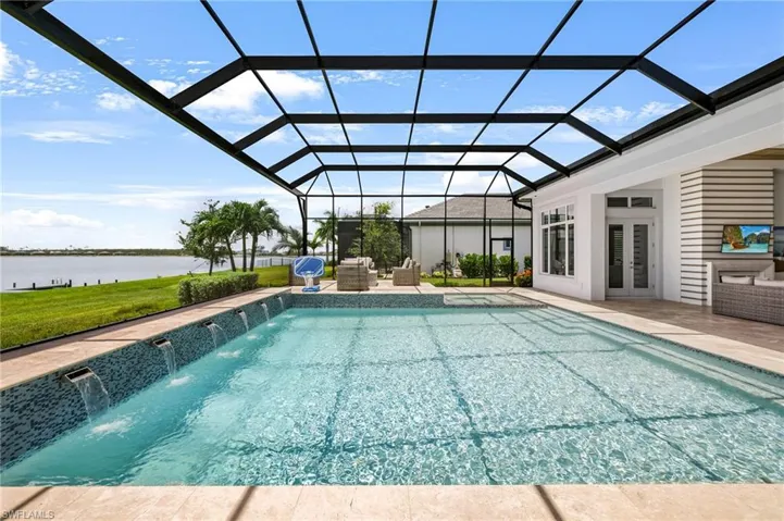 View of pool featuring a water view, glass enclosure, and pool water feature