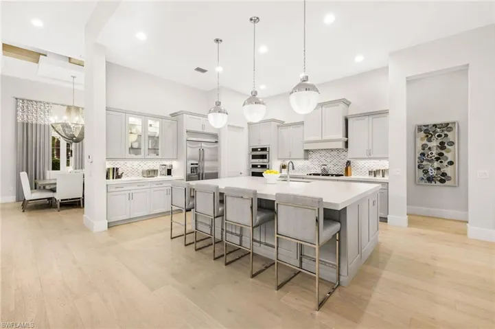 Kitchen with light hardwood / wood-style floors, a kitchen bar, stainless steel appliances, and a spacious island