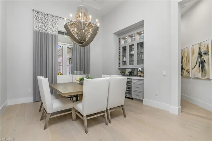 Dining area with light wood-type flooring, a notable chandelier, and wine cooler