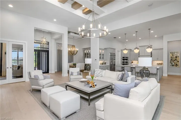 Living room with a towering ceiling, french doors, beamed ceiling, and light wood-type flooring