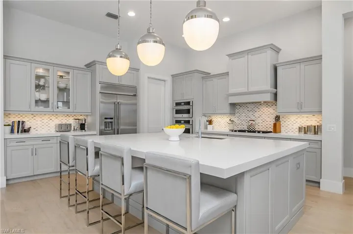Kitchen featuring a kitchen island with sink, a breakfast bar, sink, backsplash, and appliances with stainless steel finishes