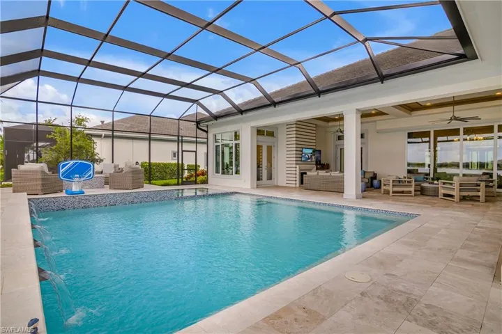 View of swimming pool with ceiling fan, glass enclosure, an outdoor hangout area, and pool water feature
