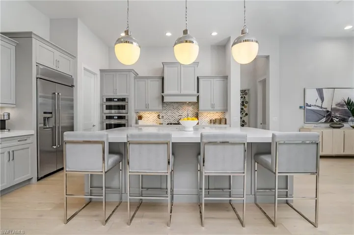 Kitchen featuring pendant lighting, a large island, appliances with stainless steel finishes, and a kitchen breakfast bar