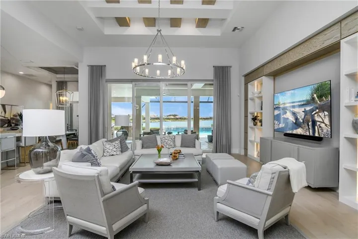 Living room with light hardwood / wood-style floors, a tray ceiling, and a notable chandelier