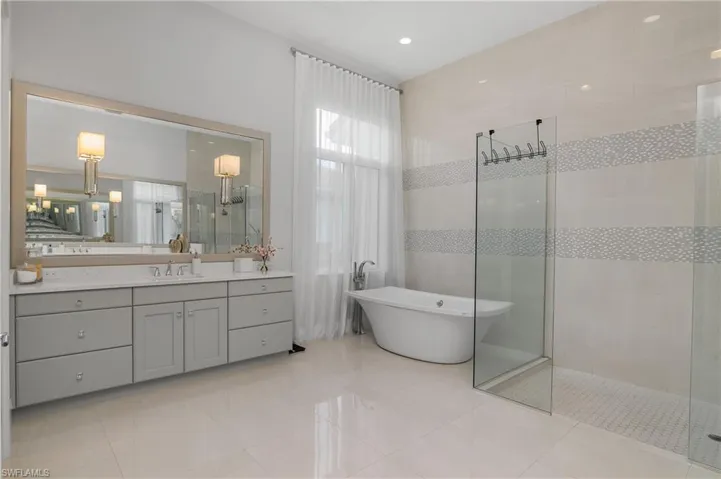 Bathroom featuring tile patterned flooring, vanity, and shower with separate bathtub