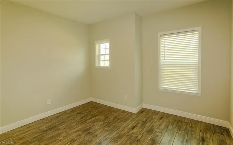 Empty room with dark wood-style floors and baseboards
