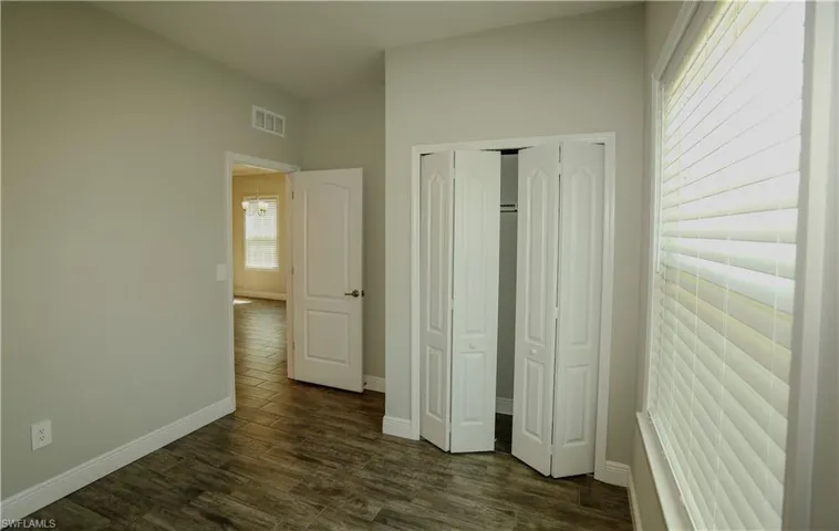 Unfurnished bedroom featuring dark wood-style flooring and a closet
