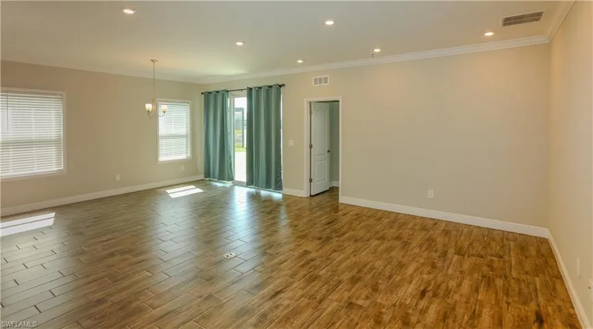 Spare room with dark wood finished floors, crown molding, and a chandelier