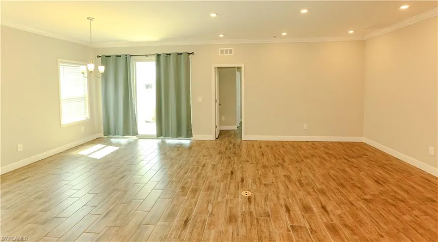 Empty room with ornamental molding, a chandelier, and light wood-type flooring