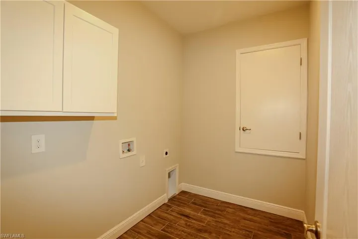 Laundry area with wood finish floors, electric dryer hookup, cabinet space, and hookup for a washing machine