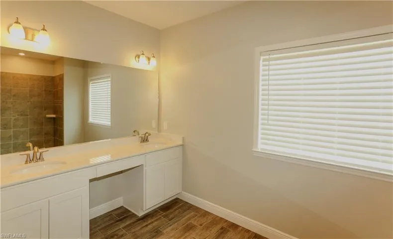 Full bathroom with double vanity, wood tiled floors, and tiled shower