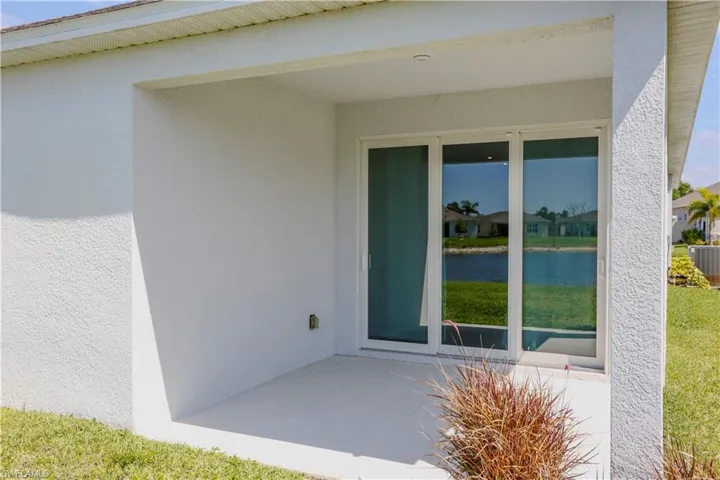 View of exterior entry featuring stucco siding and a patio
