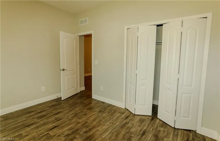 Unfurnished bedroom featuring a closet and dark wood-style floors