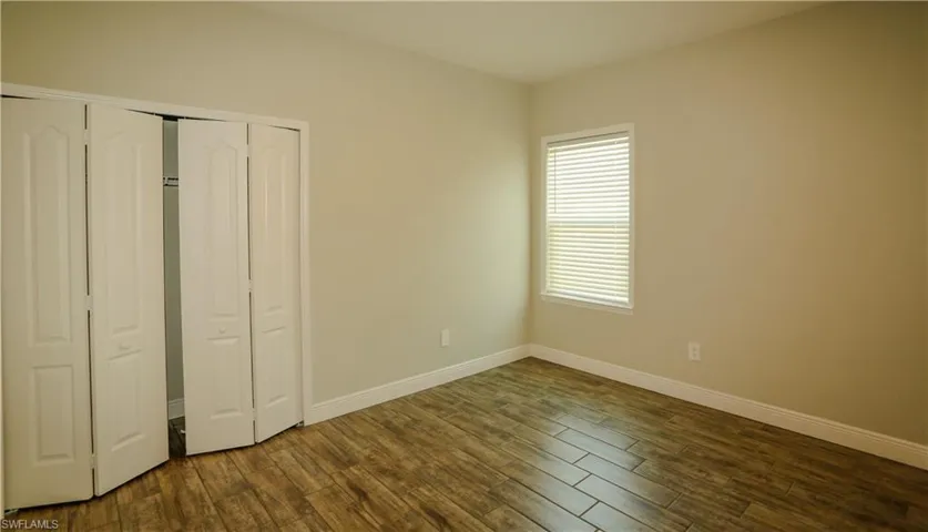 Unfurnished bedroom featuring dark wood-style floors and a closet