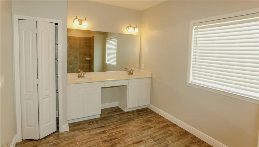 Bathroom featuring double vanity, wood finish floors, and a closet