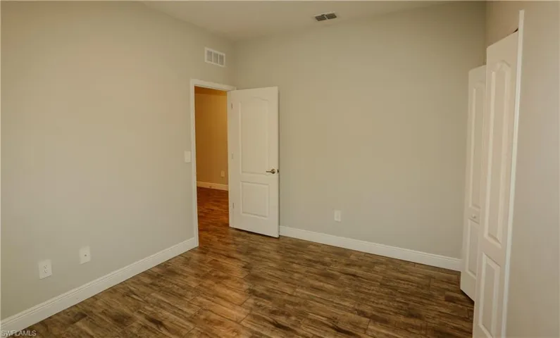 Unfurnished room featuring baseboards and dark wood-style floors