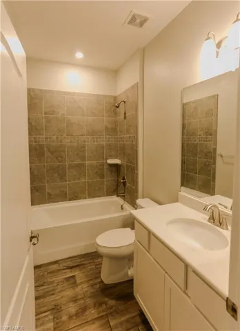 Bathroom featuring vanity, dark wood-style floors,  shower combination, and recessed lighting