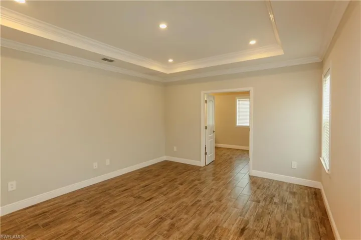Unfurnished room with wood finished floors, crown molding, recessed lighting, and a raised ceiling