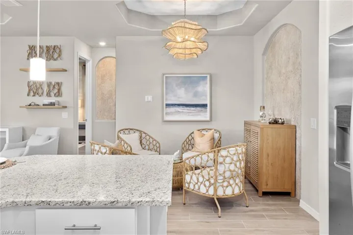 Dining space with wood finish floors, a chandelier, a tray ceiling, and arched walkways