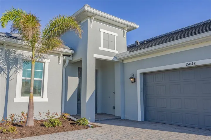 View of exterior entry featuring stucco siding, an attached garage, and decorative driveway