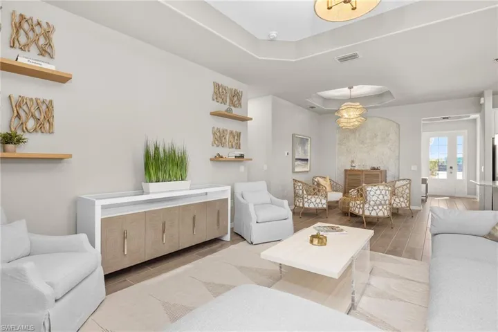 Living area featuring a raised ceiling, wood tiled floors, and french doors