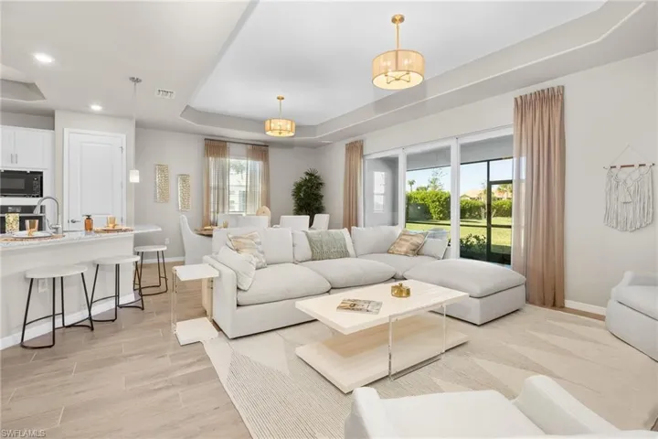 Living area with a tray ceiling, light wood-type flooring, and recessed lighting