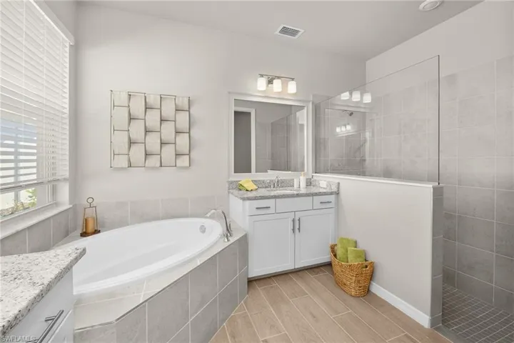 Bathroom with vanity, a bath, a walk in shower, and wood tiled floors
