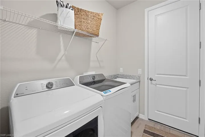 Laundry room featuring washer and dryer, cabinet space, and light wood-style floors