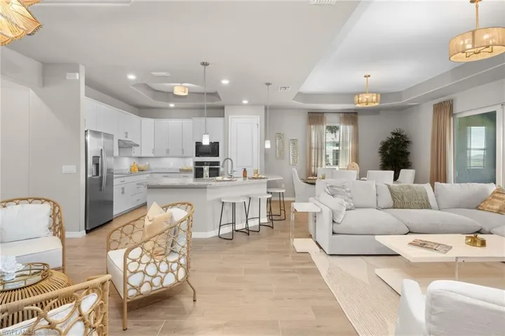 Living room with a raised ceiling, light wood-type flooring, recessed lighting, and a chandelier