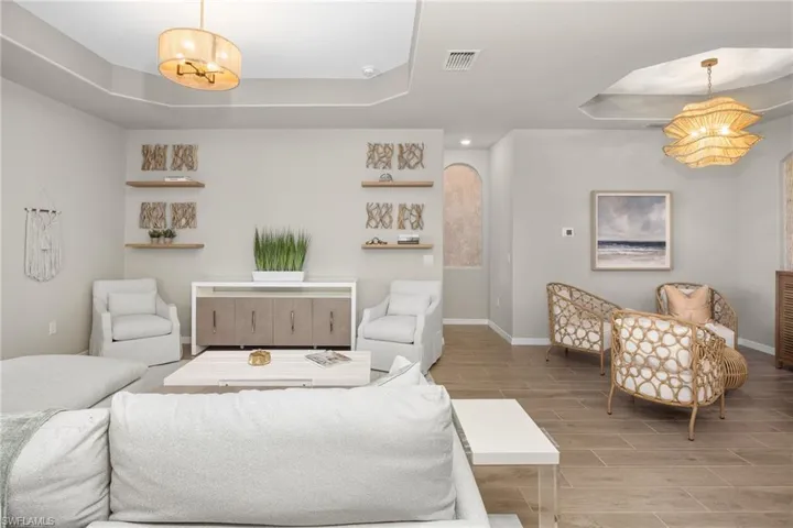 Living area with a raised ceiling, wood finish floors, a chandelier, and recessed lighting