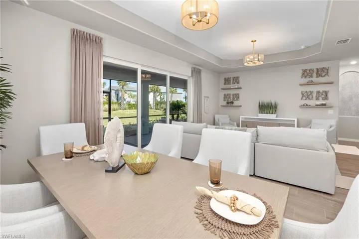 Dining area with a chandelier, a tray ceiling, and wood finished floors