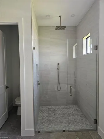 Bathroom featuring tile flooring, walk in shower, and toilet