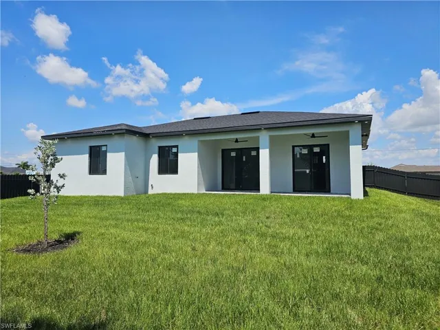 Back of property featuring ceiling fan and a lawn