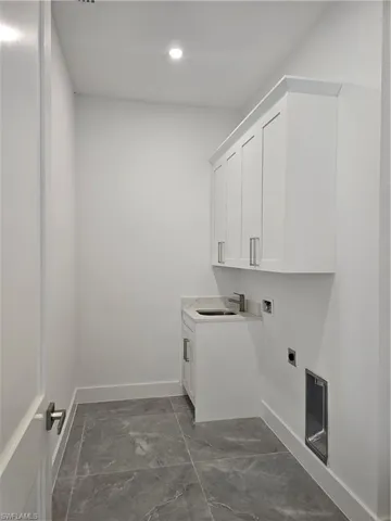 Laundry room featuring cabinets, dark tile floors, electric dryer hookup, hookup for a washing machine, and sink