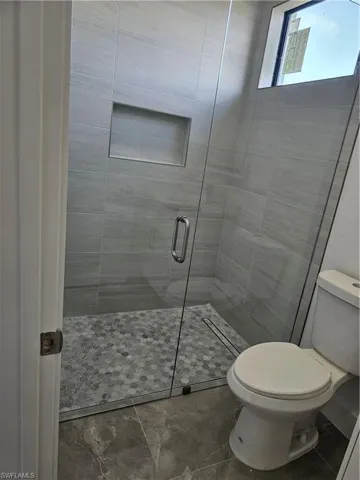 Bathroom featuring tile floors, an enclosed shower, and toilet