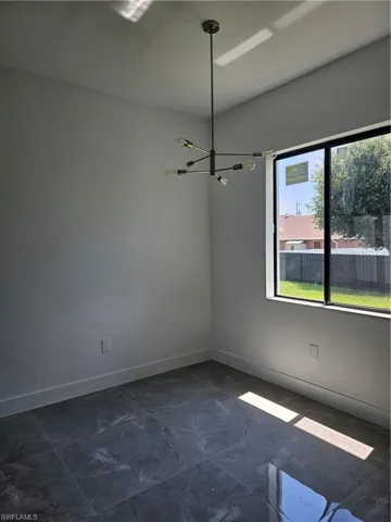 Tiled spare room featuring an inviting chandelier