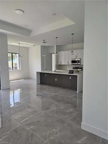 Kitchen featuring tile flooring, white cabinetry, a tray ceiling, and pendant lighting