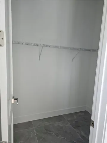 Walk in closet with dark tile flooring