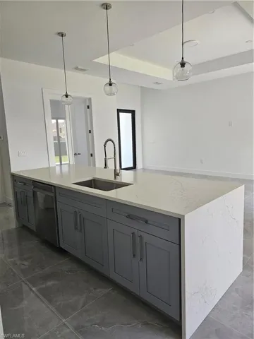 Kitchen featuring dishwasher, a center island with sink, sink, and pendant lighting