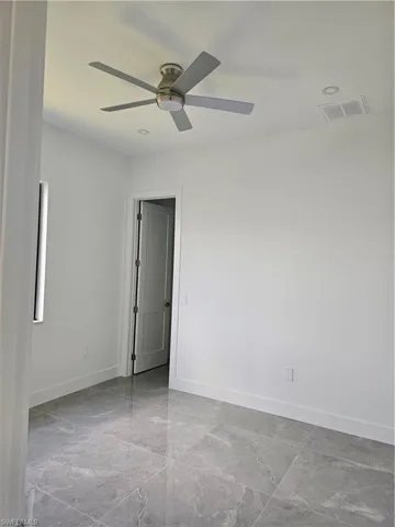 Unfurnished room with ceiling fan and light tile flooring