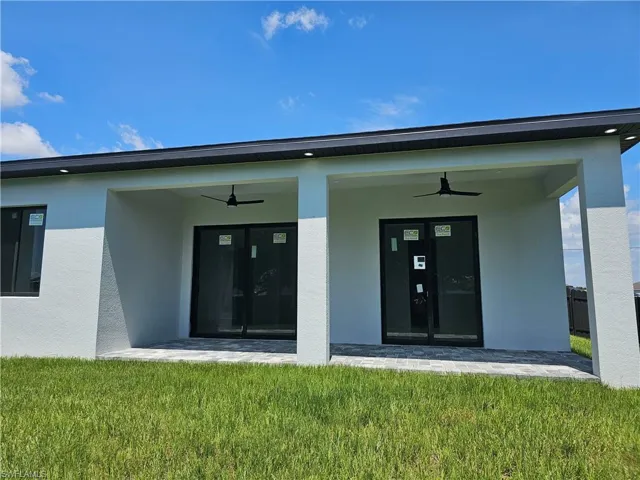 Doorway to property featuring ceiling fan, french doors, and a lawn