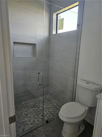 Bathroom with tile floors, a shower with door, vanity, and toilet