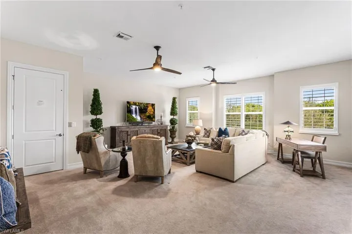 Living area with light colored carpet and ceiling fan