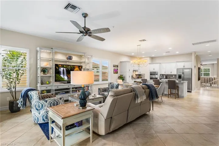 Living room featuring ceiling fan, hanging lights, light tile patterned flooring, and healthy amount of natural light