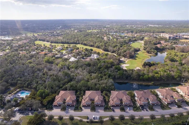 Aerial view of property and surrounding area featuring a large body of water, nearby suburban area, and a local golf course