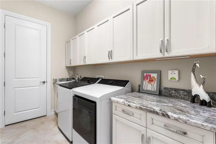Laundry area featuring cabinet space, washer and dryer, and light tile patterned floors