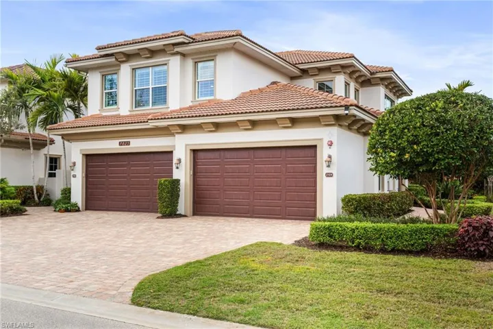 Coach home. stucco siding, driveway, a tile roof, and a front yard