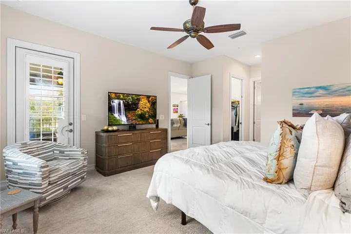 Bedroom featuring access to outside, light carpet, a walk in closet, and ceiling fan